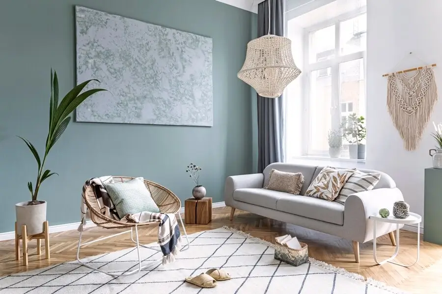 Elegant bedroom with light grey walls, a bed, modern furniture, and natural sunlight streaming through large windows.